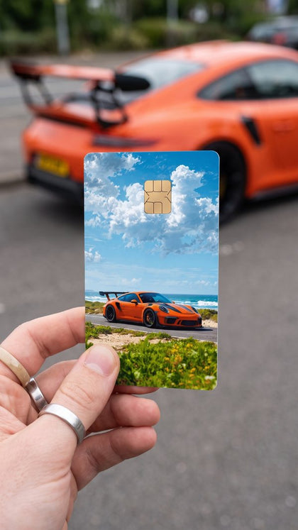 A personalized car card sticker held up, orange sports car