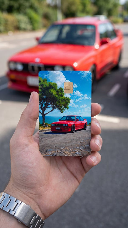 A personalized car card sticker held up, red classic car
